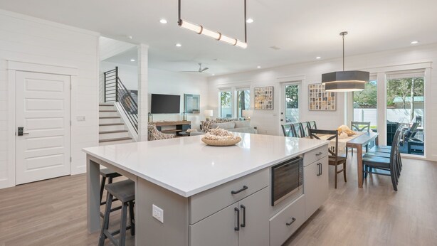 A modern kitchen with a large island, built-in appliances, and a dining area with a view. - Tango! Beach House for 26 Guests! Plus Golf Cart! (Santa Rosa Beach)