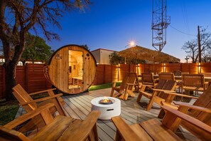 A wooden deck with lounge chairs and a circular wooden structure with a door, surrounded by a wooden fence. - Desert Retreat: Heated Pool • Sauna • Theater (Austin)