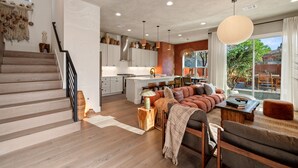 Een modern interieur met een trap, een zithoek met een bank, een eethoek en een keuken.