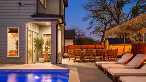 Een modern huis met zwembad, buitenmeubilair en een overdekt terras.