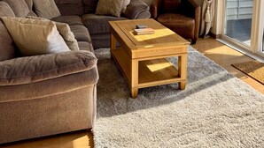 Ein Wohnzimmer mit einem braunen Ecksofa, einem Holztisch, einer Stehlampe und einem großen Spiegel an der Wand.