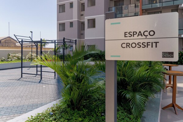 A sign for 'ESPAÇO CROSSFIT' with a metal workout structure and greenery in the background. - Charlie Rio Energy Porto Maravilha (Rio de Janeiro)