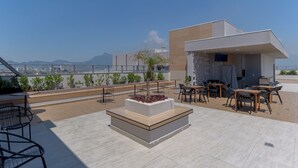 A rooftop terrace with outdoor seating, a central planter, and a view of the cityscape. - Charlie Rio Energy Porto Maravilha (Rio de Janeiro)