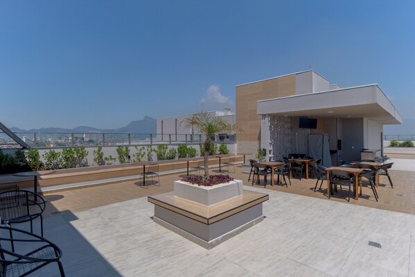 A rooftop terrace with outdoor seating, a central planter, and a view of the cityscape. - Charlie Rio Energy Porto Maravilha (Rio de Janeiro)