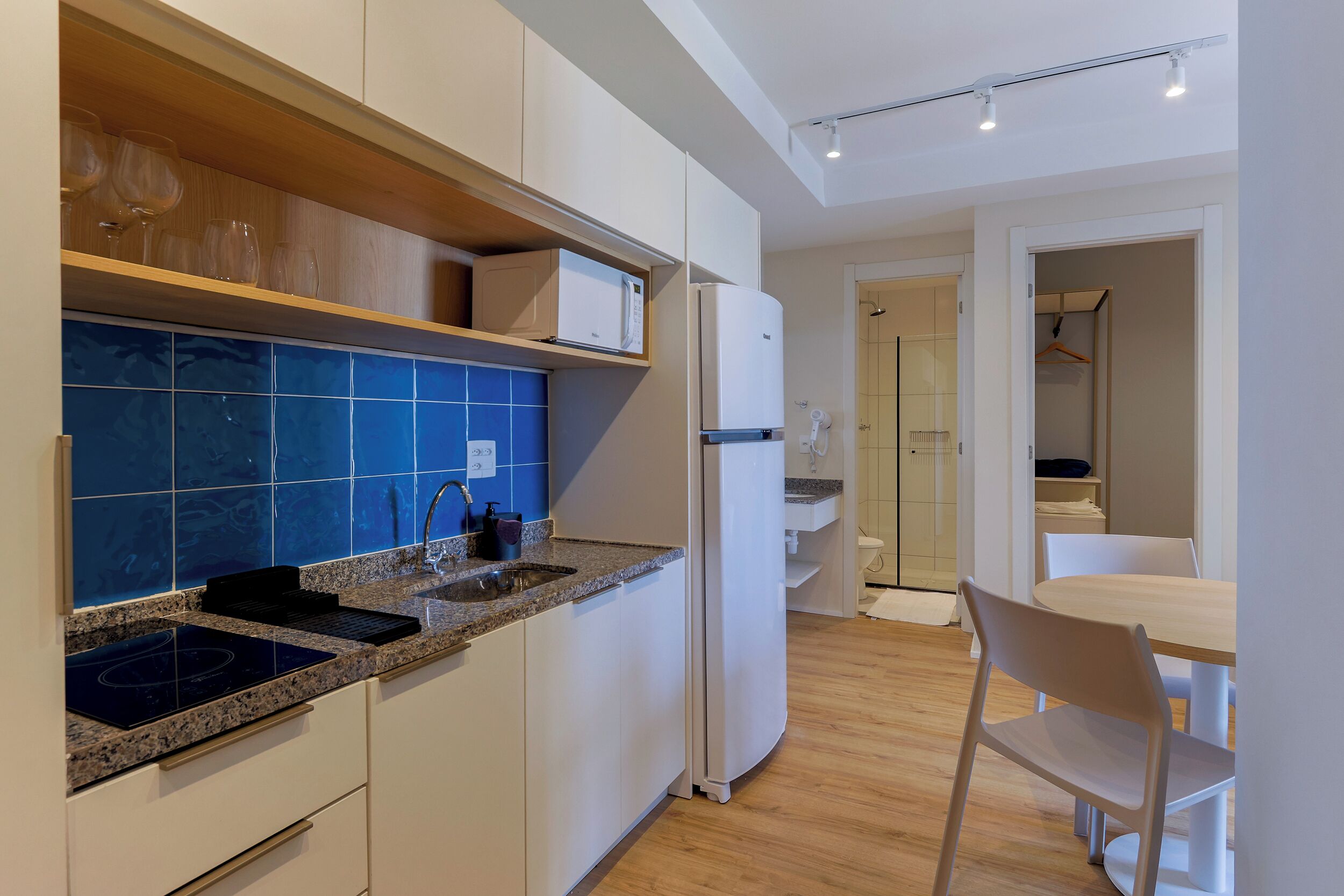 Una cucina moderna con forno a microonde integrato, lavello e zona pranzo con tavolo e sedie.