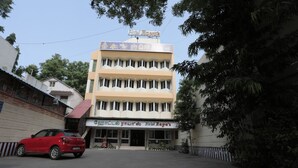 A multi-story hotel with a sign reading 'Hotel Reyat' and a red car parked in front. - Hotel Rayas (Kumbakonam)