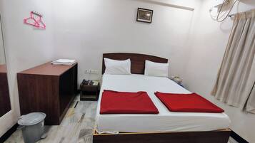 Habitació d'hotel amb llit, escriptori, telèfon, paperera i un quadre a la paret.