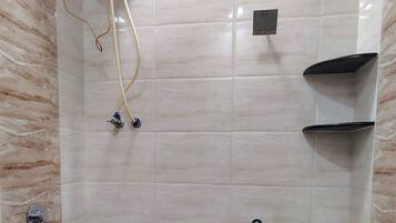A bathroom with a toilet, a bidet, a water heater, and a bucket.