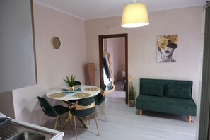 A dining area with a round table, chairs, a pendant light, a sofa, a clock, and a painting on the wall. - Altamu Guesthouse • Total comfort for up to 4 guests (Campania)