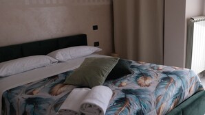 Una cama con colcha estampada, cabecera verde y almohada blanca.