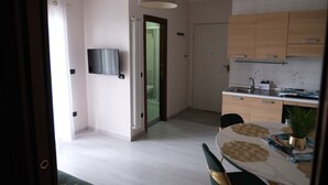 Una cocina moderna con televisor de pantalla plana, gabinetes de madera y un comedor con mesa y sillas.