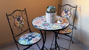 Una mesa pequeña y redonda con sillas, una planta en maceta y un objeto decorativo sobre la mesa.