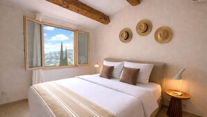 A bedroom with a large bed, a window with a view, and three hats on the wall. - Charming villa - stylish, quiet, relaxing ***New at FeWo*** (Cavalaire-sur-Mer)