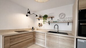 A modern kitchen with a wooden countertop, a black sink, a built-in oven, and a clock on the wall. - Charming villa - stylish, quiet, relaxing ***New at FeWo*** (Cavalaire-sur-Mer)