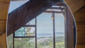 A room with a large oval mirror reflecting a view of a balcony and a cityscape.