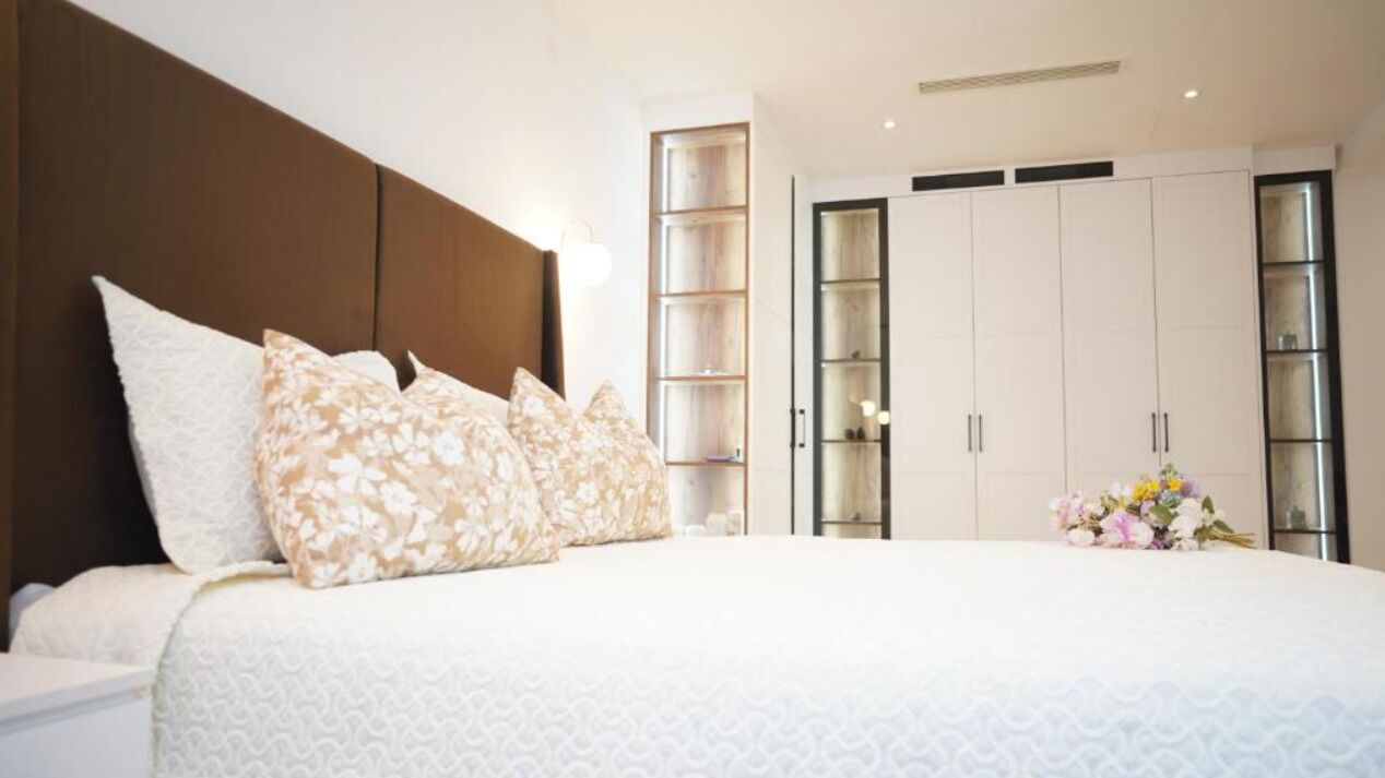 A bedroom with a large bed, a wardrobe, and a nightstand.