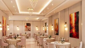 A spacious hotel dining area with round tables, elegant chairs, and modern chandeliers. - Palette Hotel Millennium City Centre (Gurugram)