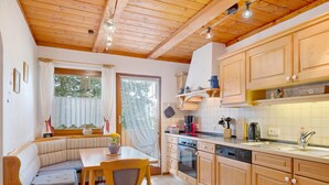 A cozy kitchen with wooden cabinets, a dining area with a bench, and a window with curtains. - Apartment Sommerruhe in Jostal near Titisee (Titisee-Neustadt)