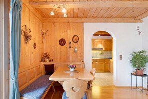 Een houten interieur met een eettafel, een bankje en een keuken op de achtergrond.