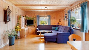 A wooden-paneled room with a sofa, a table, and a TV. - Apartment Sommerruhe in Jostal near Titisee (Titisee-Neustadt)