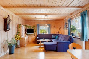 Ein Zimmer mit Holzwänden, einer Couch, einem Tisch und einem Fernseher.