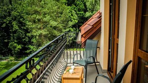 A balcony with a table and chairs, a wooden table, and a view of a forested area.