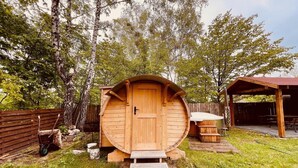 Una cabaña de madera con puerta, escalones y un banco afuera.