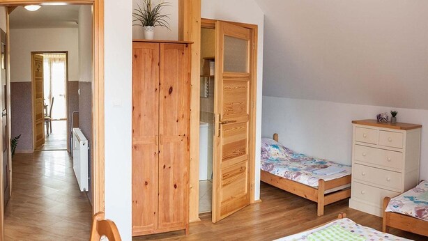 Un dormitorio con un armario de madera, una cama individual, una mesita de noche y un aparador.