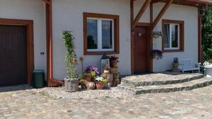 Un edificio con ingresso in pietra, travi in legno e un portico con gradini.