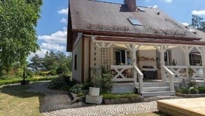 Una casa con portico, camino e giardino.