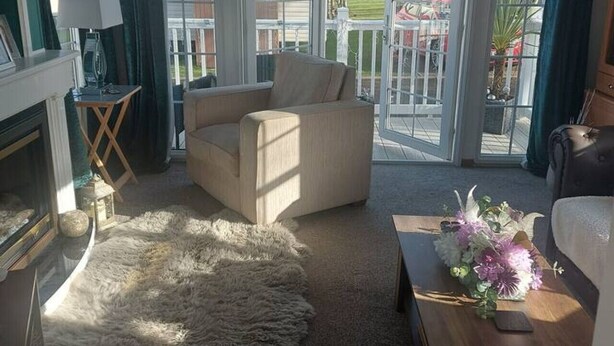 Un salon comprenant un canapé, une table basse, une cheminée et une vue dégagée sur l’extérieur grâce à de grandes portes vitrées.