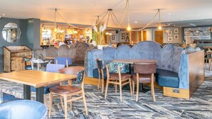 Un restaurant avec des banquettes, des tables et un coin bar.