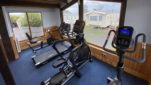 Une salle de sport équipée de tapis de course, de vélos elliptiques et d’un appareil d’aviron.