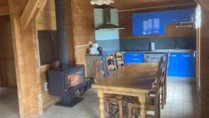 A wooden interior with a central table, chairs, a stove, and blue cabinets. - A serene interlude in the heart of the Jura mountains (Lent)