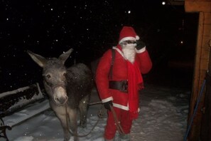 A person in a red outfit with a belt and boots, standing next to a donkey in a snowy environment. - A serene interlude in the heart of the Jura mountains (Lent)