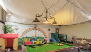 A room with a pool table, a couch, and a children's play area. - The Hereford - with pool table, play barn & more! (Dilhorne)