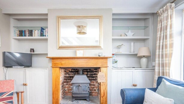 Una sala de estar con chimenea, televisor y estantería.