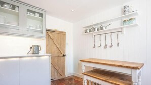 Una cocina con armarios blancos, una puerta de madera y un colgador para utensilios.