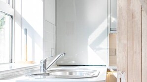 Una cocina moderna con un lavamanos de acero inoxidable, un ventanal y armarios de madera.