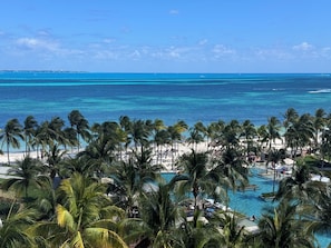 Ein Strandresort mit Palmen, einem Schwimmbad und Blick aufs Meer.