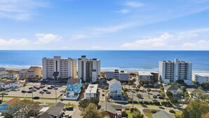 Eine Küstenstadt mit Hotels direkt am Strand, einem Parkplatz und freiem Blick auf das Meer.