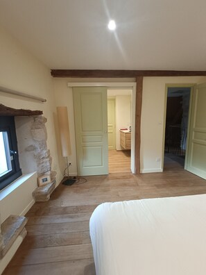 A bedroom with a bed, a stone wall, a window, and a door leading to another room. - “Pistachio” Room with Shared Pool, Communal Terrace and Wi-Fi (Beaumont sur Grosne)