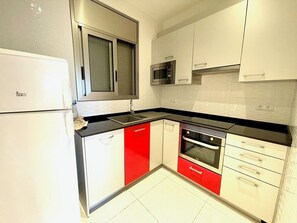 A kitchen with white cabinets, a stainless steel refrigerator, a microwave, and a stove. - SAONA VILLAS (VN LOUNI): villa sleeps 6, private pool, wifi, fans (Les Tres Cales)