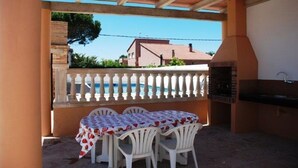 Una terrazza esterna con tavolo e sedie, una piscina e un barbecue.
