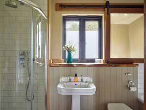 Un baño con ducha, lavabo, inodoro y ventana con vistas.