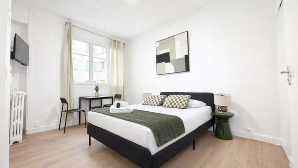 A bedroom with a bed, a desk, a chair, a radiator, and a TV. - Charmant Studio Paris 15eme - Proche Tour Eiffel (Paris)