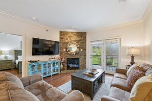 Ein Wohnzimmer mit Kamin aus Stein, einem Flachbildfernseher, einer Couch und einem Couchtisch.