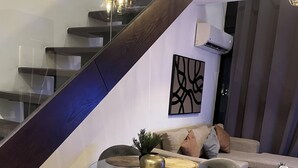 Ein modernes Interieur mit einem Glastisch, grau gepolsterten Stühlen, einer Couch und einer Treppe.