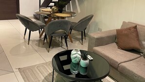 Ein modernes Wohnzimmer mit Glastisch, grauem Sofa und einer Treppe mit Holzwandung.