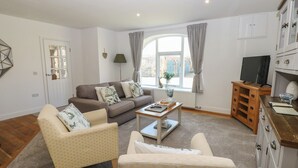 A living room with a sofa, two armchairs, a coffee table, a TV, and a cabinet. - Castle View Cottage (Bedale)